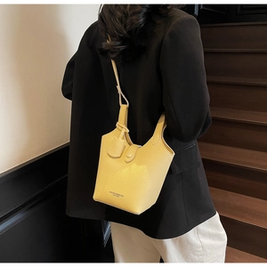 Detail of yellow litchi pattern bucket bag showing textured leather and brand logo