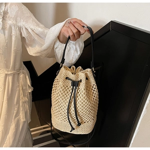 Detailed close-up of natural beige hollow woven bucket bag with black drawstring closure