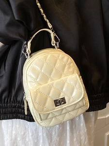 Schicker gesteppter beiger Mini-Rucksack mit Metallkette am Model für den täglichen Stil
