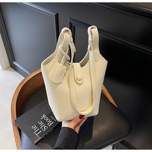 Close-up of minimalist lychee pattern bucket bag with ring handle on leather seat