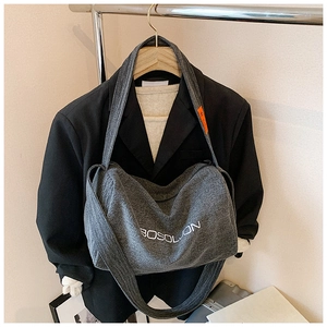 Dettaglio della borsa tote in denim grigio con ricamo bianco e etichetta arancione sulla tracolla