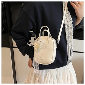 Dettaglio della borsa a tracolla bianco crema con fiocco in pizzo e perle decorative