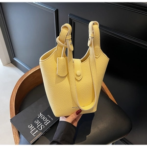 Close-up of yellow litchi pattern leather bucket bag on black leather chair background