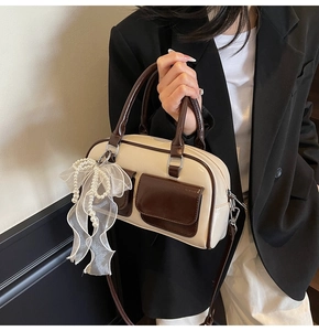 Detail of Boston bag featuring shiny patent leather, white lace bow and pearl charms