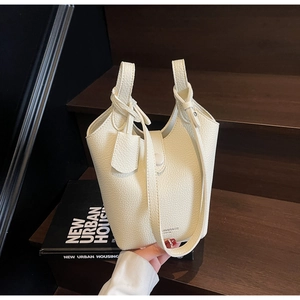 Close-up of beige lychee grain bucket bag with JIN&BAGS logo and top handle detail