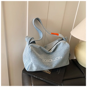 Dettaglio della borsa tote in denim azzurro con logo bianco e tracolla arancione