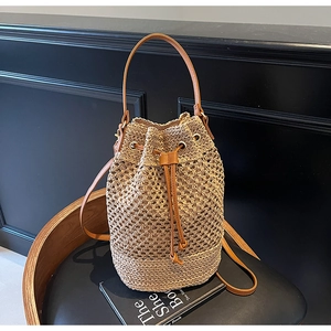 Detail of woven straw bucket bag with drawstring closure and brown leather strap