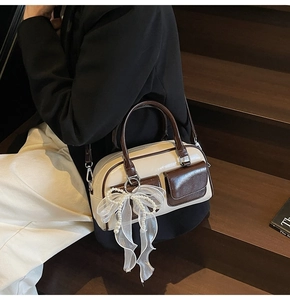 Detail of Boston bag in cream and brown leather featuring a pearl mesh bow charm