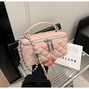 Detail of pink quilted PU leather box bag with dual zippers and woven chain strap