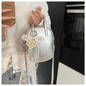 Dettaglio mini borsa a tracolla argento con fiocco in pizzo e ciondolo cuore di perle