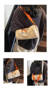Detail of off-white canvas barrel bag with adjustable orange strap and 1985 text