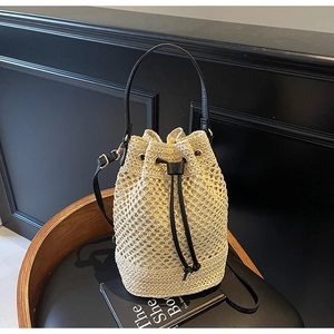 Detail of the woven hollow bucket bag with black drawstring closure and gold hardware