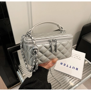 Detail of silver quilted vanity case with metal chain strap and dual zippers