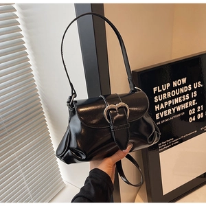 Détail d'un sac à bandoulière en cuir verni noir avec boucle argentée en forme de cœur