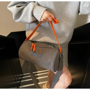 Detail of canvas barrel tote bag with 1985 embroidery and orange contrast straps