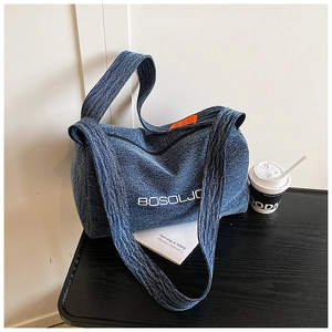 Dettaglio ravvicinato del tessuto denim blu navy strutturato e del logo bianco della borsa