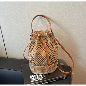 Detailed shot of hollow woven bucket bag with brown leather drawstring and straps