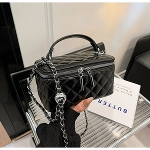 Detail view of black quilted faux leather vanity bag with silver chain and metal adjuster ball