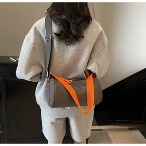 Detail view of the cylinder tote bag with blue 1985 embroidery and orange strap