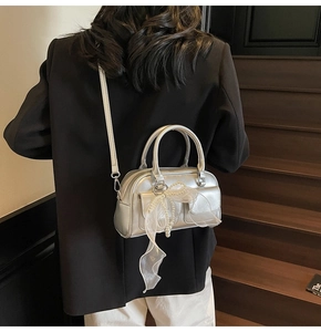 Detail of silver metallic handbag featuring pearl accents and white mesh bow decoration