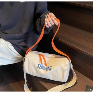 Close-up of retro canvas barrel bag with 1985 embroidery and orange contrast handle