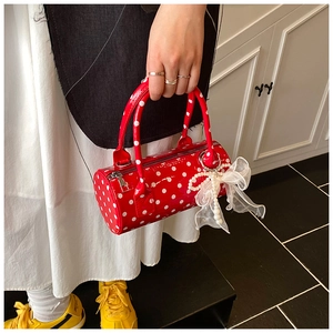 Close-up of red polka dot cylinder handbag featuring lace bow and pearl charm detail