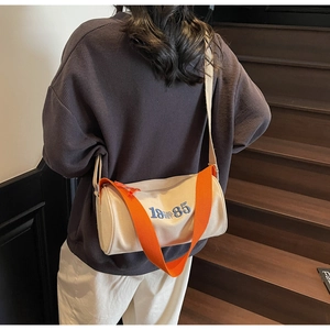 Detail of a casual canvas cylinder tote bag with orange strap and blue 19-85 embroidery