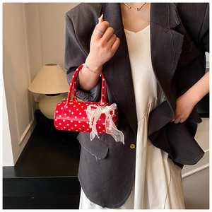 Close-up of red polka dot cylinder handbag with lace bow and pearl charm detail