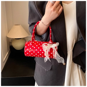 Close-up of red polka dot barrel bag with organza bow and elegant pearl chain detail