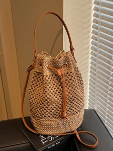 Hollow straw woven bucket bag with leather drawstring handle and crossbody strap