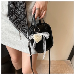 Dettaglio mini borsa nera con ciondolo a cuore di perle e fiocco in pizzo elegante