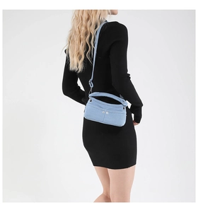 Dettaglio della mini borsa a tracolla in denim azzurro con rivetti e cinturino