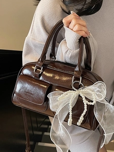 Brown glossy patent leather Boston bag with a large pearl butterfly bow accent for women
