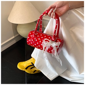 Red patent leather polka dot cylinder handbag with pearl bow charm detail