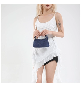 Dettaglio di una mini borsa in denim blu scuro con fibbie in metallo argentato