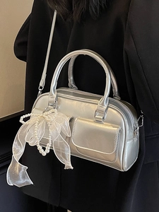Metallic silver Boston handbag with mesh bow and pearl charms worn by a model