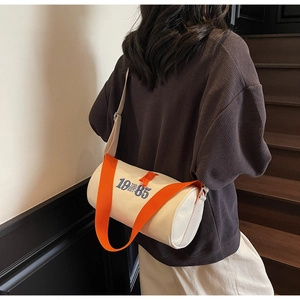Detail of canvas barrel bag with vintage 1985 embroidery and bright orange strap