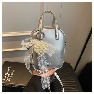 Mini borsa argento con ciondolo a cuore di perle e fiocco di pizzo su un libro