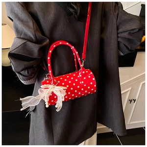 Close-up of red polka dot cylinder bag with lace ribbon and pearl charm detail