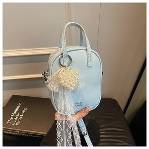 Dettaglio mini borsa a tracolla celeste con ciondolo a cuore di perle e nastro di pizzo