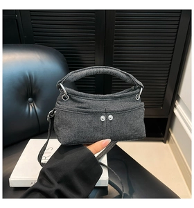Vista dettagliata del tessuto denim grigio scuro con rivetti argentati e finiture in metallo