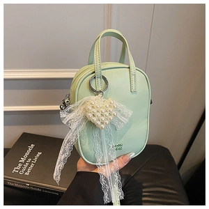 Dettaglio borsa in pelle PU verde menta con ciondolo a cuore e fiocco in pizzo