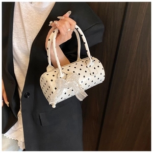 Detailed view of white polka dot cylinder bag with lace bows and pearl charms