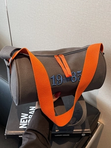 Casual grey canvas cylinder tote bag with 1985 embroidery and orange shoulder strap