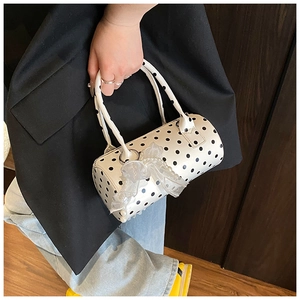 Detailed view of polka dot cylindrical handbag with lace bow and pearl charm