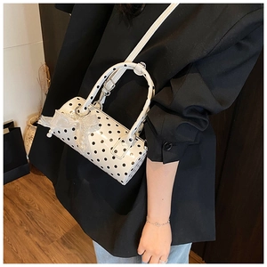 Polka dot cylinder handbag featuring a delicate white lace bow and pearl charm detail