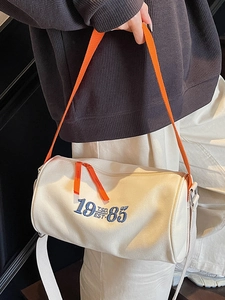 Chic beige canvas cylinder tote bag with vibrant orange strap for casual travel and gym use