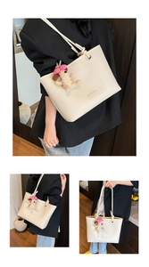 Detail of cream tote bag with textured leather and cute plush dog charm accessory