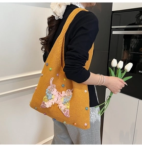 Detail of yellow knit tote bag featuring 3D fabric butterflies and colorful bead accents