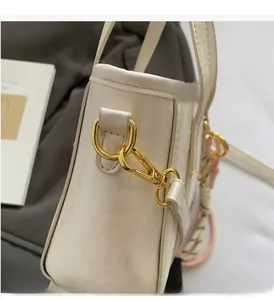 Macro detail of high-quality gold metal D-ring and clasp on elegant cream bucket bag
